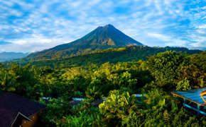 Arenal Volcano rises above the tropical forest of Costa Rica, framed by colorful lodges.