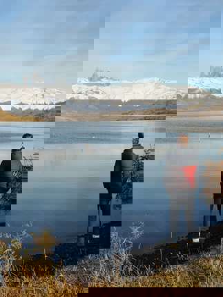 Traveler admires the reflection of the Paine Massif in a still Patagonia lake under clear skies in Torres del Paine, Chile. 