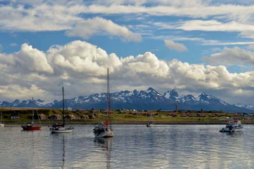 Sailboats float peacefully in Ushuaia's Beagle Channel with Patagonia's peaks behind. 