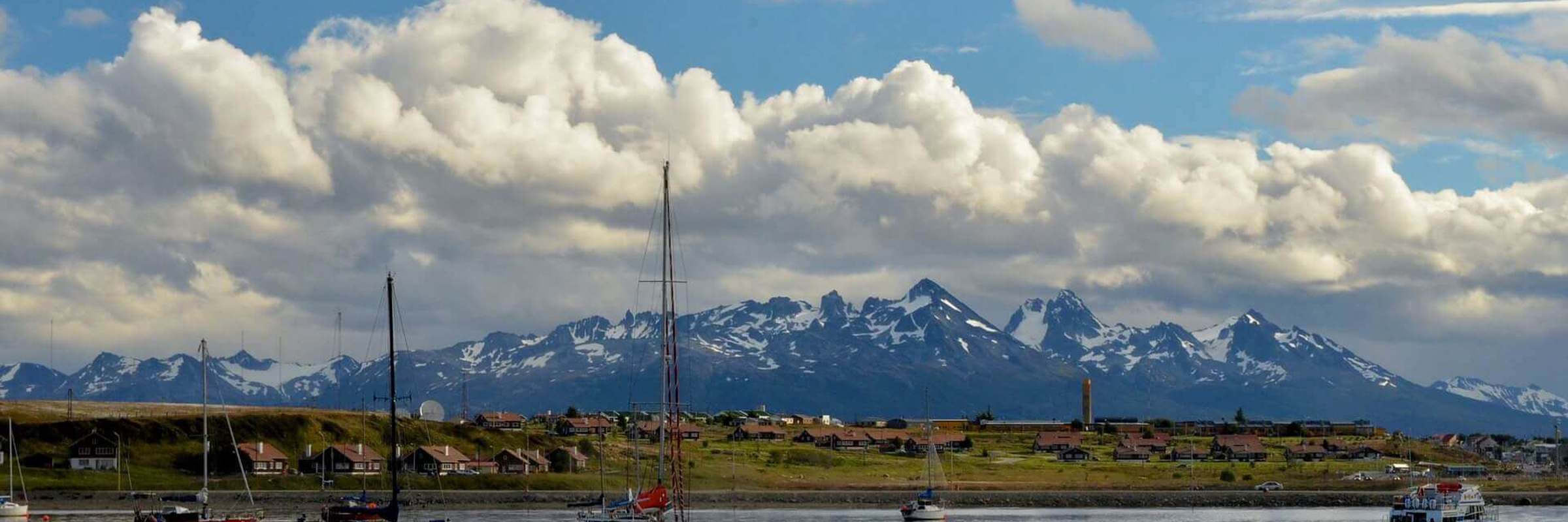 Sailboats float peacefully in Ushuaia's Beagle Channel with Patagonia's peaks behind. 