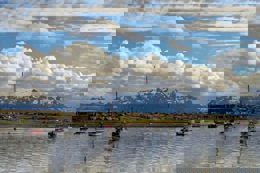 Sailboats float peacefully in Ushuaia's Beagle Channel with Patagonia's peaks behind. 