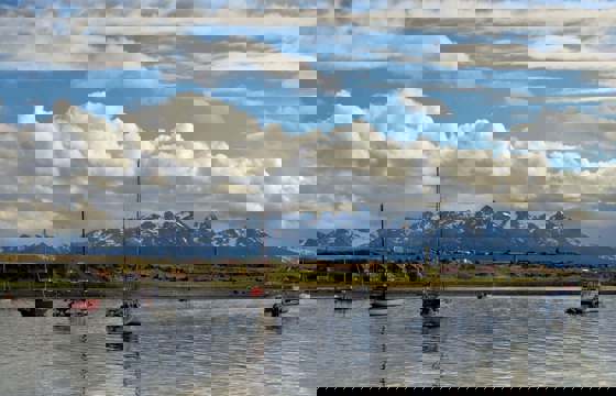 Sailboats float peacefully in Ushuaia's Beagle Channel with Patagonia's peaks behind. 