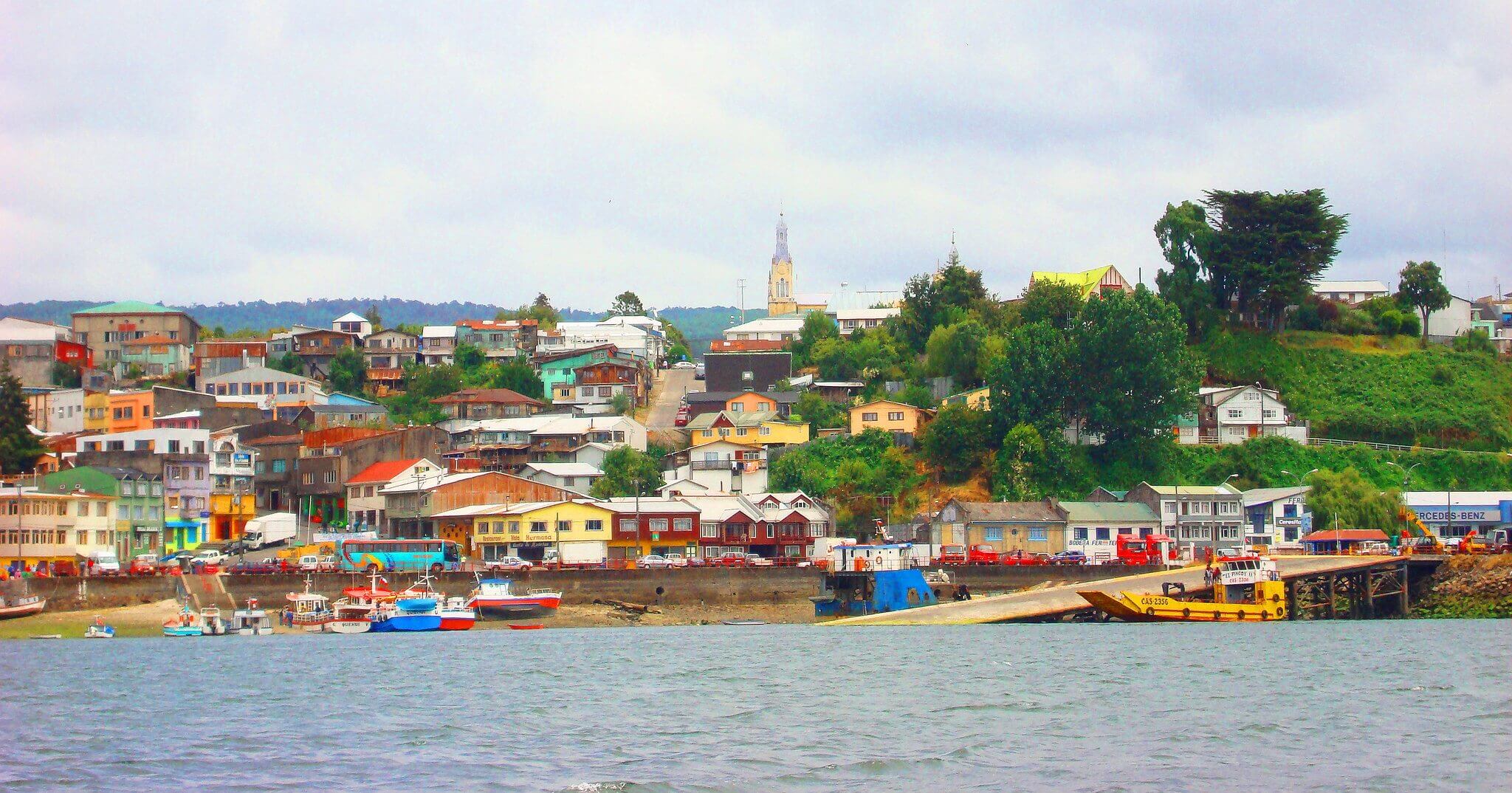 Colorful houses line the harbor of Castro on Chiloe Island, Chile, showcasing the island's iconic coastal charm and fishing culture. 