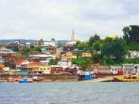 Colorful houses line the harbor of Castro on Chiloe Island, Chile, showcasing the island's iconic coastal charm and fishing culture. 