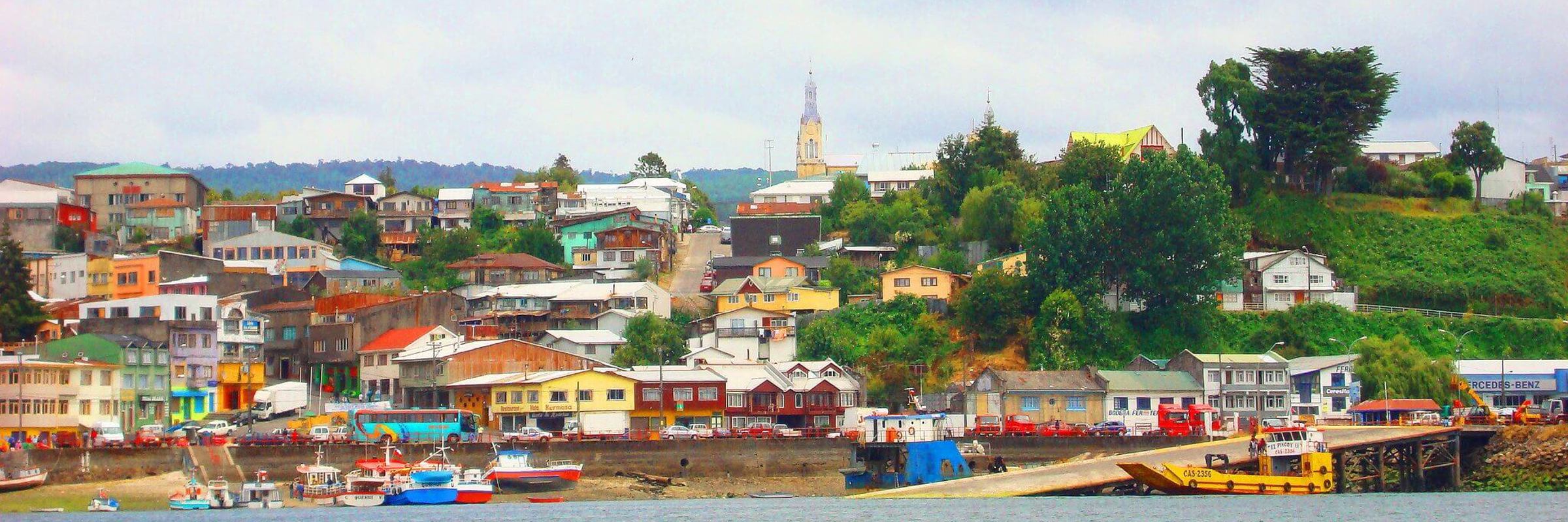 Colorful houses line the harbor of Castro on Chiloe Island, Chile, showcasing the island's iconic coastal charm and fishing culture. 