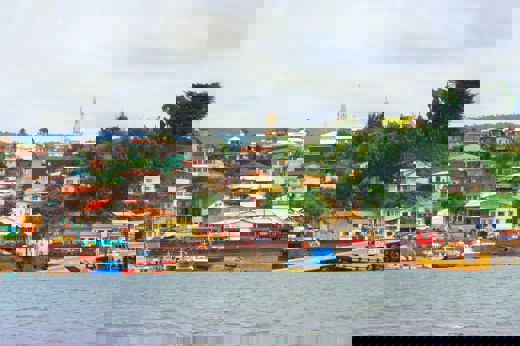 Colorful houses line the harbor of Castro on Chiloe Island, Chile, showcasing the island's iconic coastal charm and fishing culture. 