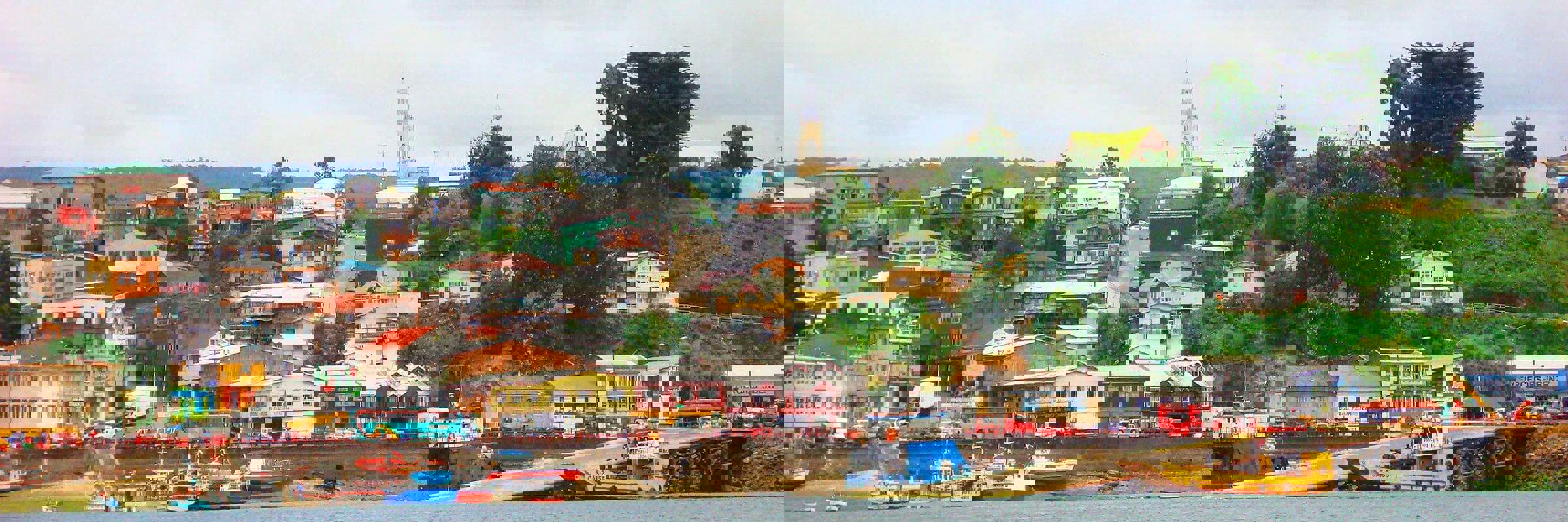 Colorful houses line the harbor of Castro on Chiloe Island, Chile, showcasing the island's iconic coastal charm and fishing culture. 
