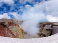 View of the steaming crater of Villarrica Volcano near Pucon, Chile, surrounded by snow and dramatic skies. 