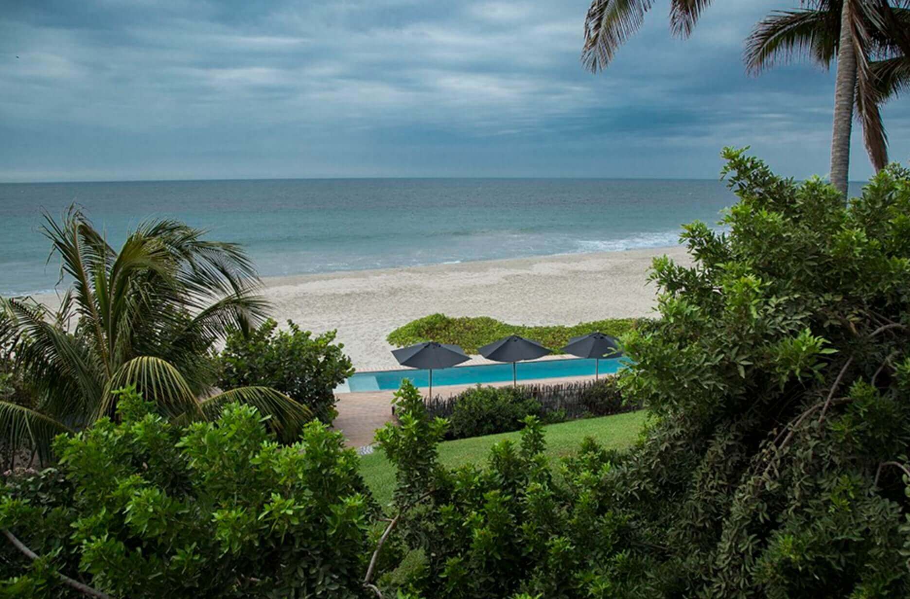 Tropical palms frame serene ocean waves at Kichic's peaceful beachfront hideaway in Mancora. 