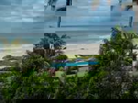 Tropical palms frame serene ocean waves at Kichic's peaceful beachfront hideaway in Mancora. 