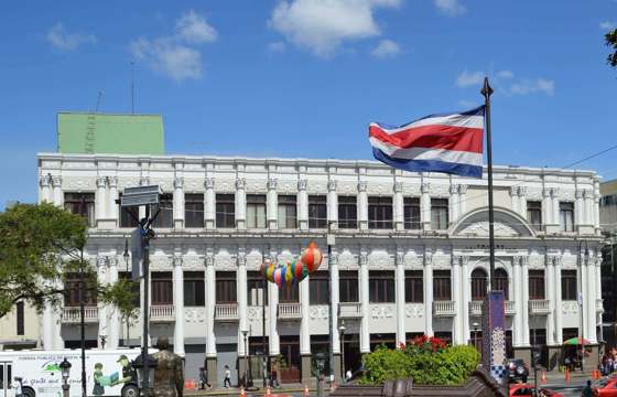A grand historic building in downtown San Jose, proudly flying the Costa Rican flag, reflects the capital's cultural and political heritage. 