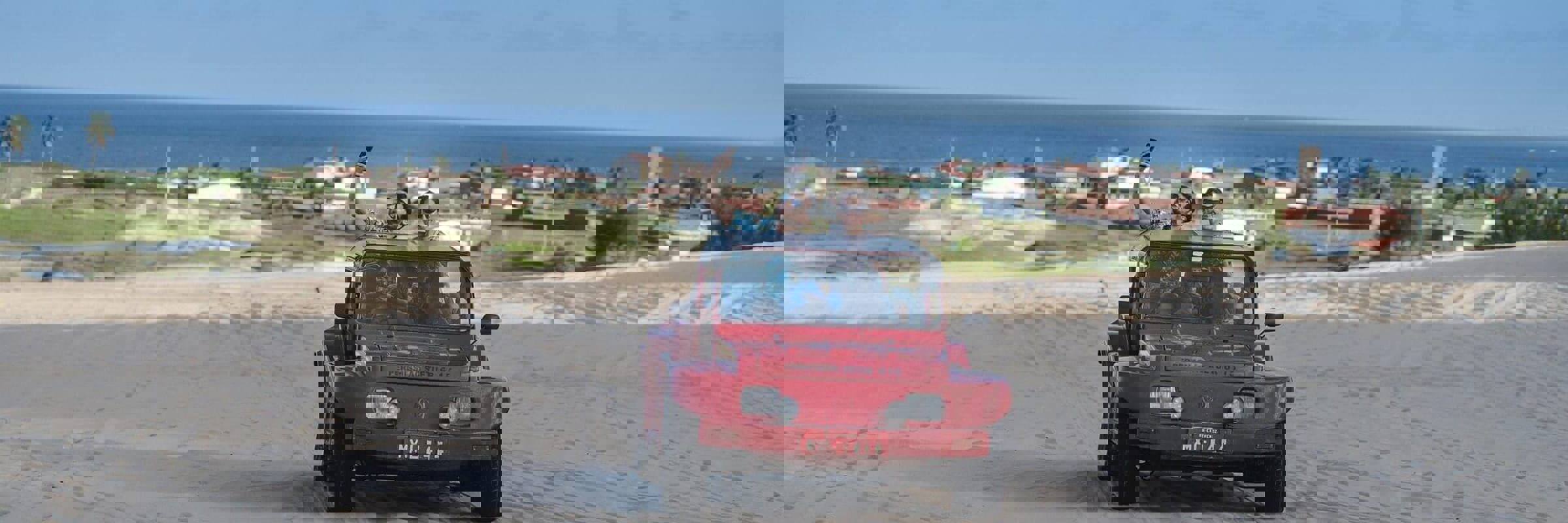Red beach buggy driving  across sand dunes in Jericoacoara with ocean and coastal town in the background. 