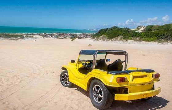 Yellow beach buggy parked on sandy beach during a scenic buggy tour near Jericoacoara, Ceara, Brazil. 