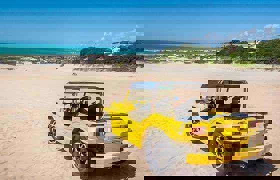 Yellow beach buggy parked on sandy beach during a scenic buggy tour near Jericoacoara, Ceara, Brazil.
