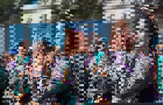 Smiling Peruvian women in traditional dress performing a folkloric dance in Lima.