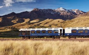 The Belmond Andean Explorer train crossing the high plans of Peru with the Andes in the background. 