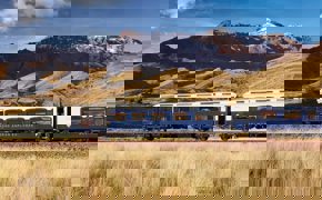 The Belmond Andean Explorer train crossing the high plans of Peru with the Andes in the background. 