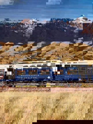 The Belmond Andean Explorer train crossing the high plans of Peru with the Andes in the background. 