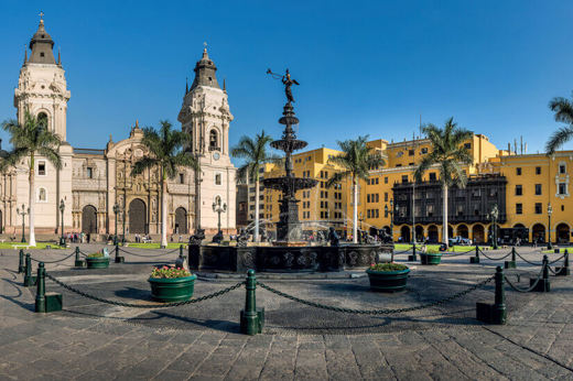 Historic Cathedral of Lima and Plaza de Armas with colonial architecture and palm trees. 