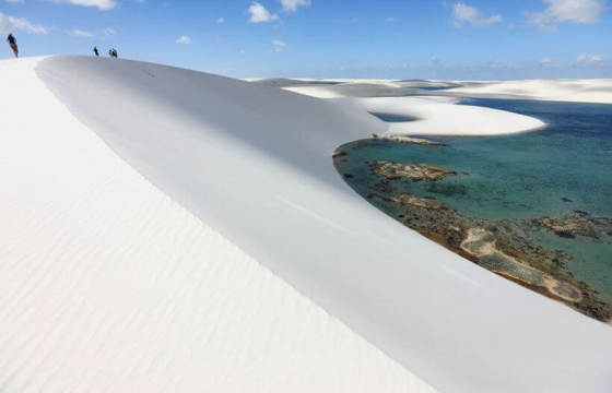 Panoramic view of bright white sand dunes and blue lagoons in Lencois Maranhenses National Park, Brazil.